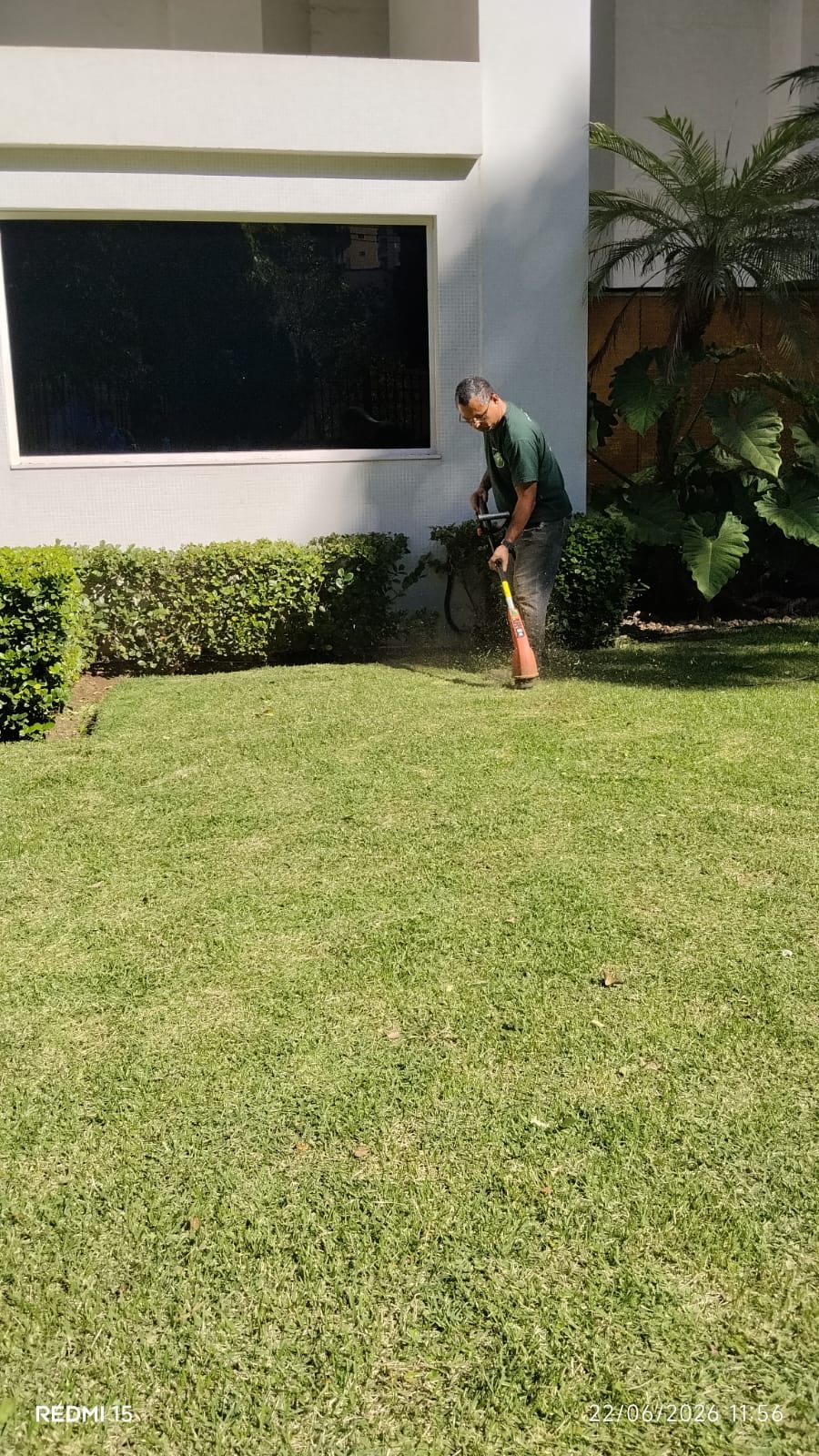 Profissional trabalhando na manutenção do jardim do condomínio